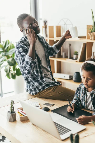 Father talking by phone while son drawing — Stock Photo