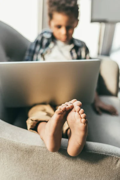 Menino com laptop em poltrona — Fotografia de Stock