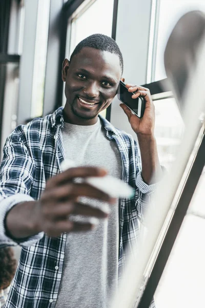 Businessman with smartphone writing on whiteboard — Stock Photo