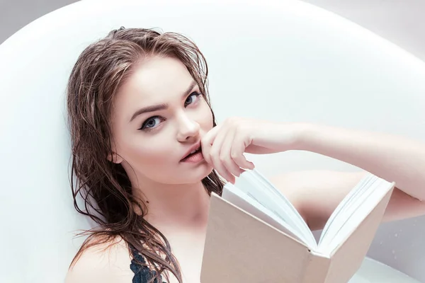 Femme avec livre couché dans le bain — Photo de stock