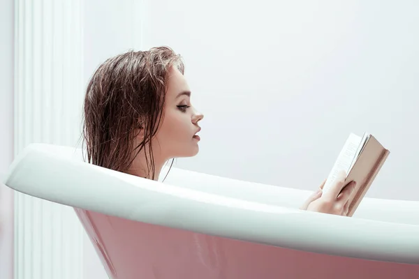 Woman reading book in bath tube — Stock Photo