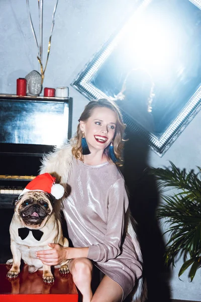 Frau mit Mops im Weihnachtsmann-Hut — Stockfoto
