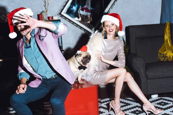 Paar mit Mops im Weihnachtsmann-Hut — Stockfoto