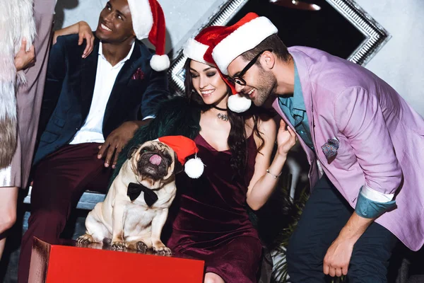 Friends with pug in santa hats — Stock Photo