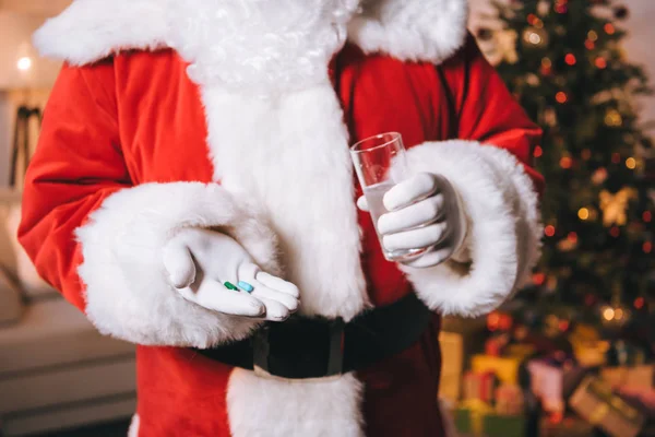 Weihnachtsmann mit Glas Wasser und Tabletten — Stockfoto