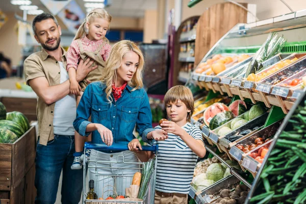 Family with shopping cart in supermarket — Stock Photo