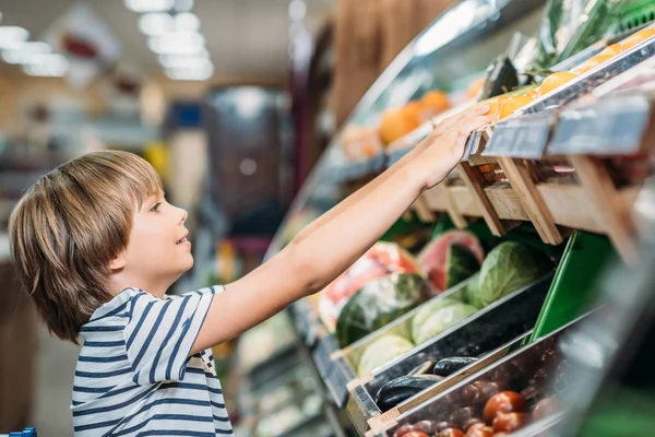 Мальчик выбирает еду в продуктовом магазине — стоковое фото