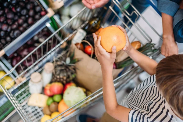 Bambino che aiuta i genitori a fare shopping — Foto stock