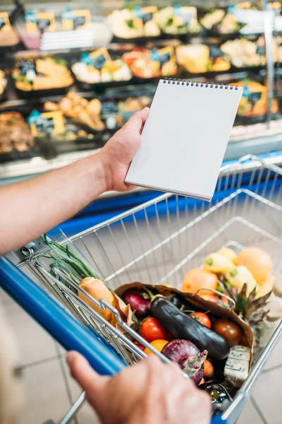 Hombre con cuaderno vacío en el supermercado - foto de stock