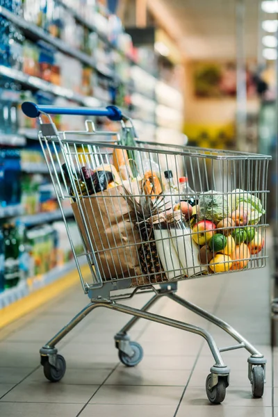 Carrito de compras con compras en el supermercado - foto de stock