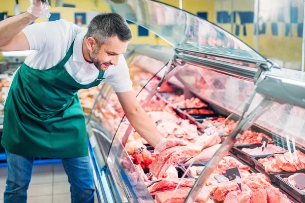 Shop assistant assorting raw meat — Stock Photo