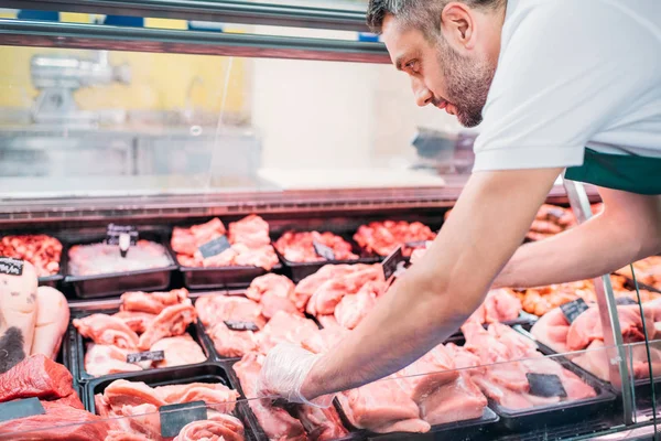 Verkäuferin sortiert rohes Fleisch — Stockfoto