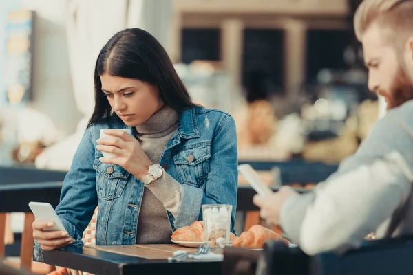 Casal olhando para smartphones no café — Fotografia de Stock