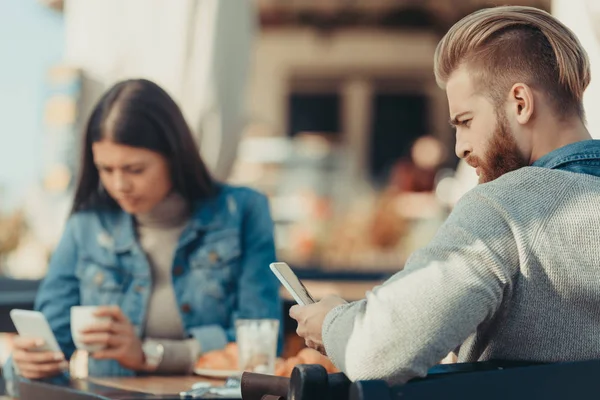 Пара смотрит на смартфоны в кафе — стоковое фото