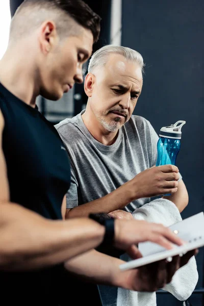 Trainer talking with senior sportsman — Stock Photo