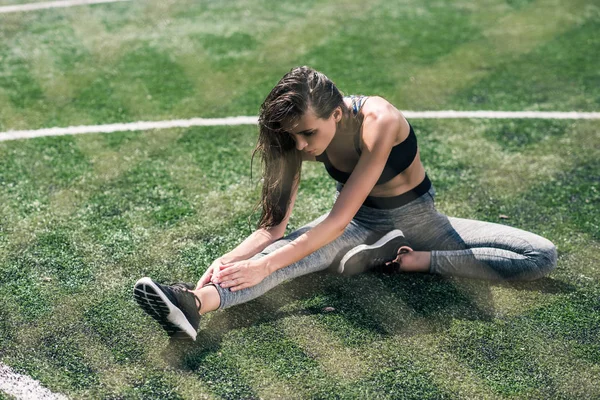 Жінка тягнеться на спортивному полі — стокове фото