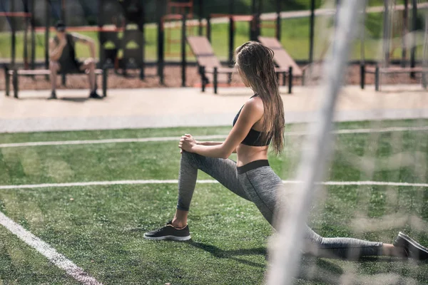 Woman stretching on sports field — Stock Photo