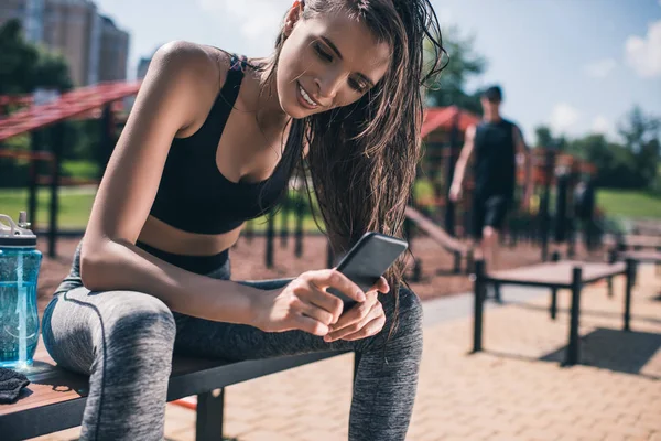 Mulher esportiva usando smartphone — Fotografia de Stock