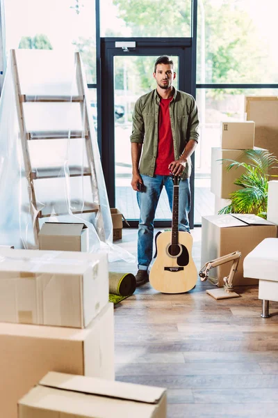 Homme avec guitare dans une nouvelle maison — Photo de stock