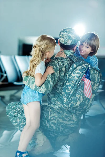 Niños abrazando padre en aeropuerto - foto de stock