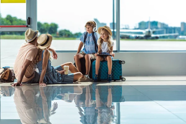 Padres e hijos esperando el embarque en el aeropuerto - foto de stock