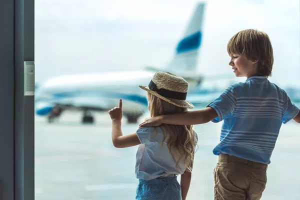Kids looking out window in airport — Stock Photo
