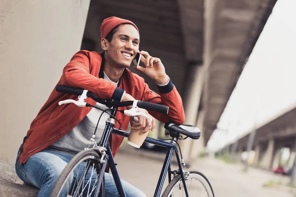 Man with bicycle talking by phone — Stock Photo