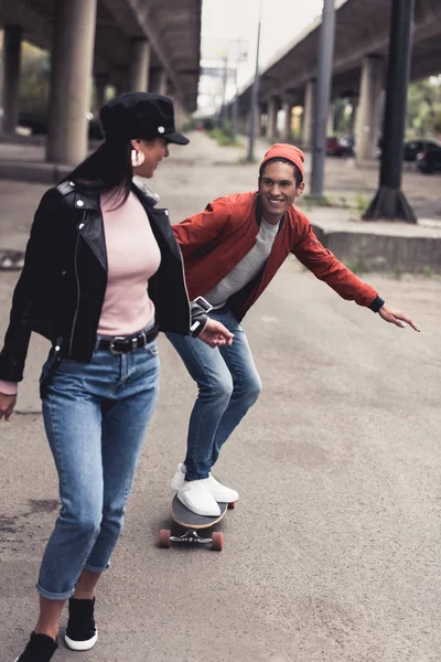 Homme équitation à petite amie sur skateboard — Photo de stock