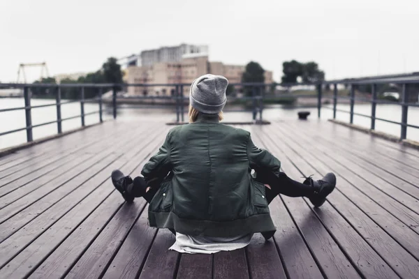 Femme assise sur une jetée en bois — Photo de stock