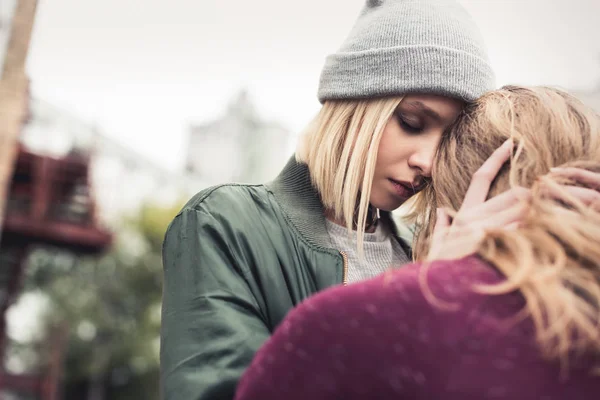 Woman embracing her sitting boyfriend — Stock Photo