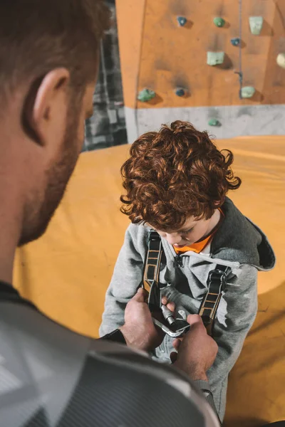 Papá asegurando hijo en arnés - foto de stock