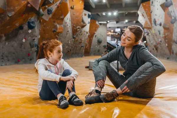 Дівчина і мама сидять на килимку в спортзалі — стокове фото