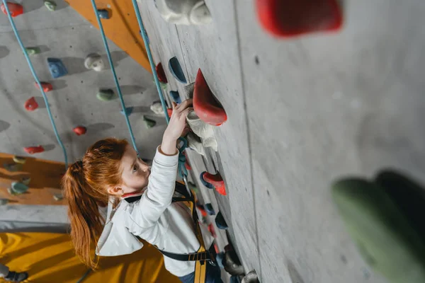Little girl climbing wall with grips — Stock Photo