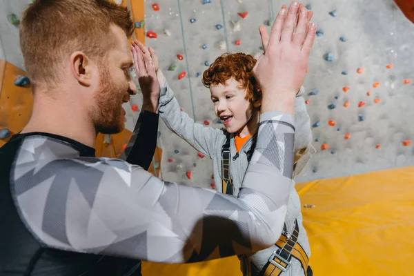 Boy in climbing harness high-fiving dad — Stock Photo