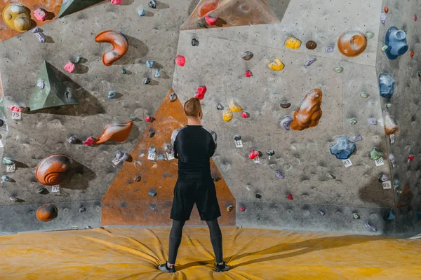 Young man in front of climbing wall — Stock Photo