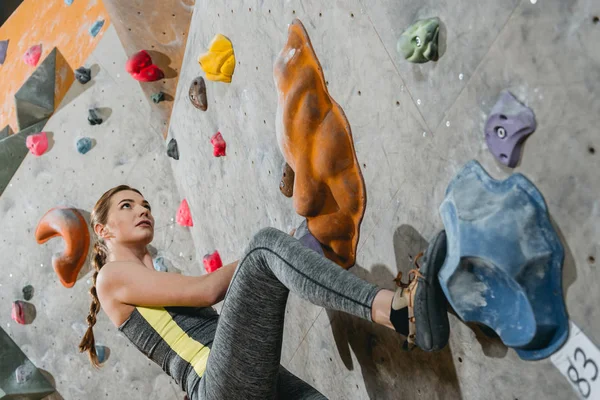 Woman climbing wall with grips — Stock Photo