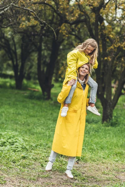 Madre e hija en impermeables en el campo - foto de stock