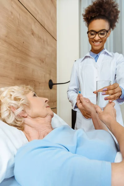 Doctor handing sick woman medicine — Stock Photo
