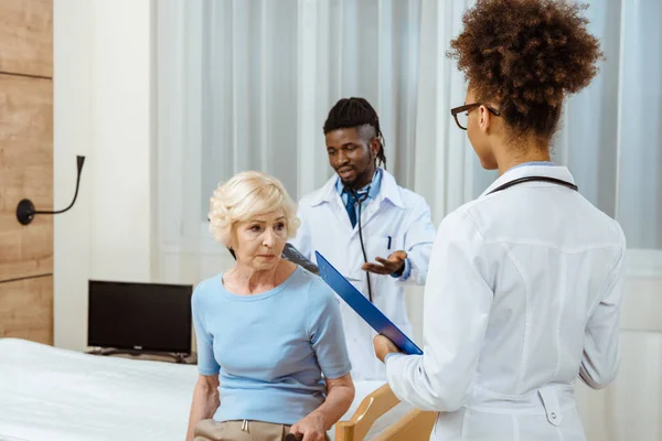 Elderly woman with doctors in hospital — Stock Photo