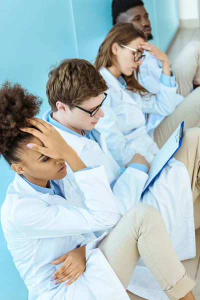 Troubled doctors sitting in hospital corridor — Stock Photo