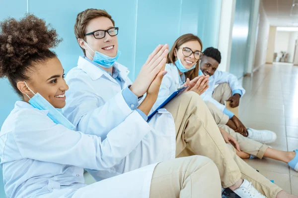 Усміхнені лікарі сидять в лікарняному коридорі — стокове фото