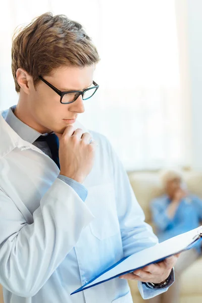 Doctor reading notes on clipboard — Stock Photo