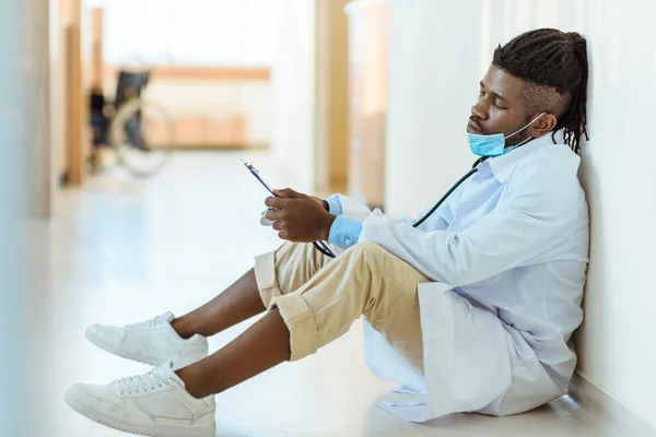 Arzt liest Notizen auf Krankenhausflur — Stockfoto