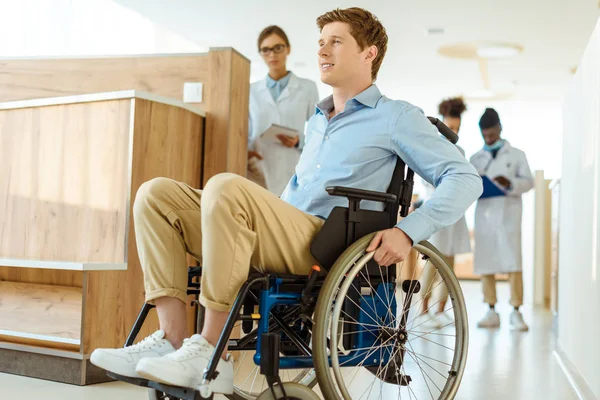 Hombre en silla de ruedas en el pasillo del hospital - foto de stock