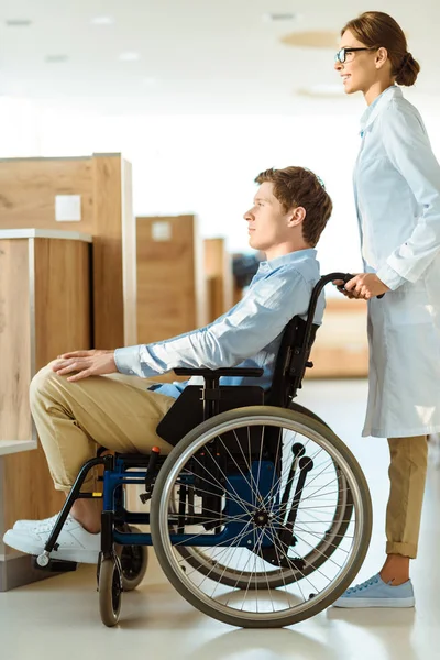 Doctor balanceo hombre en silla de ruedas - foto de stock