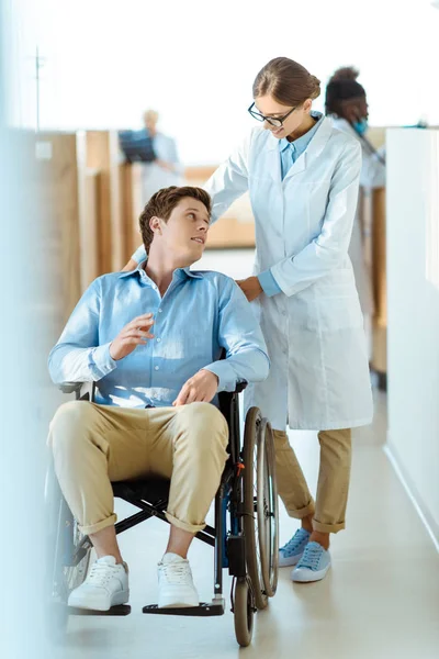 Doctor ayudando a hombre discapacitado en el hospital - foto de stock