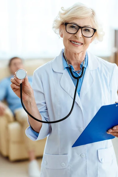 Médecin principal avec stéthoscope et presse-papiers — Photo de stock