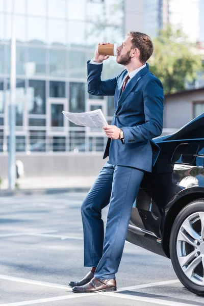 Businessman drinking coffee at car — Stock Photo