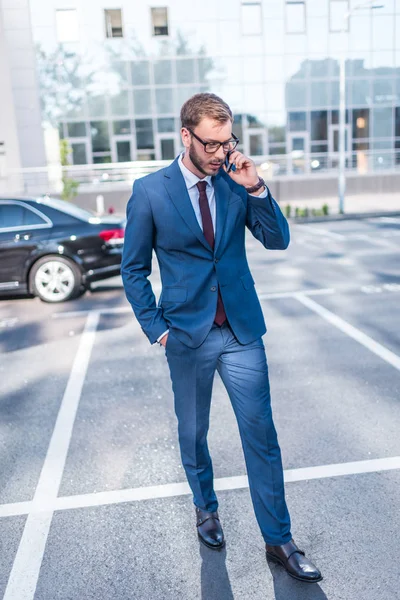 Uomo d'affari con smartphone sul parcheggio — Foto stock