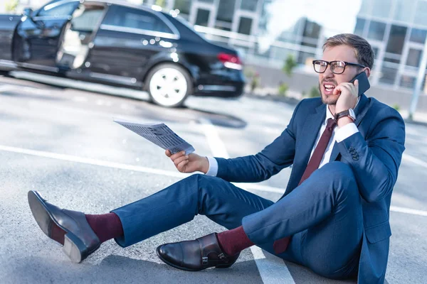 Stressed businessman with newspaper and smartphone — Stock Photo